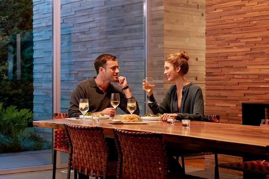 A couple eating at their dining table in warm lighting.